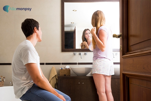 Une femme se regardant dans un miroir et se maquillant, sans prêter attention à son partenaire à côté d'elle, illustrant l'égocentrisme des pervers narcissiques.
