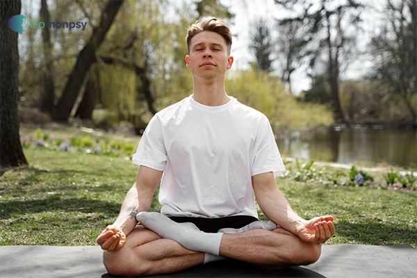 Jeune homme pratiquant la méditation de pleine conscience dans un parc